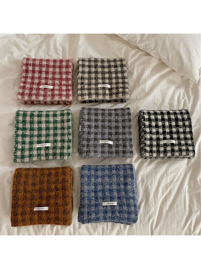 Seven checkered scarf styles folded on a white bed