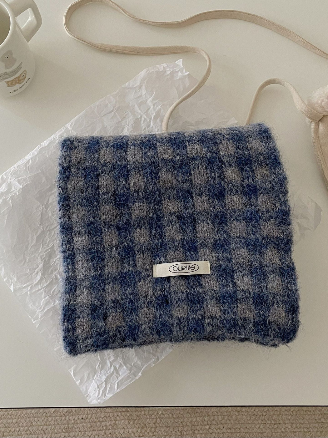 Blue Coffee checkered scarf folded on a light tabletop