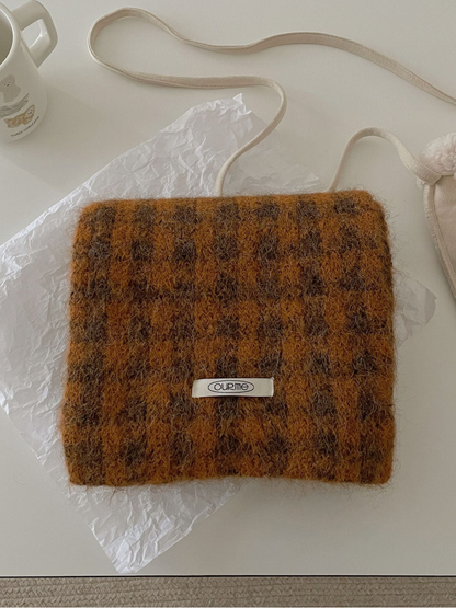 Orange checkered scarf folded on a light tabletop