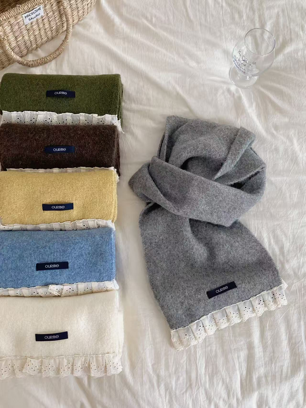 Folded lace-trim scarves beside a draped Gray scarf
