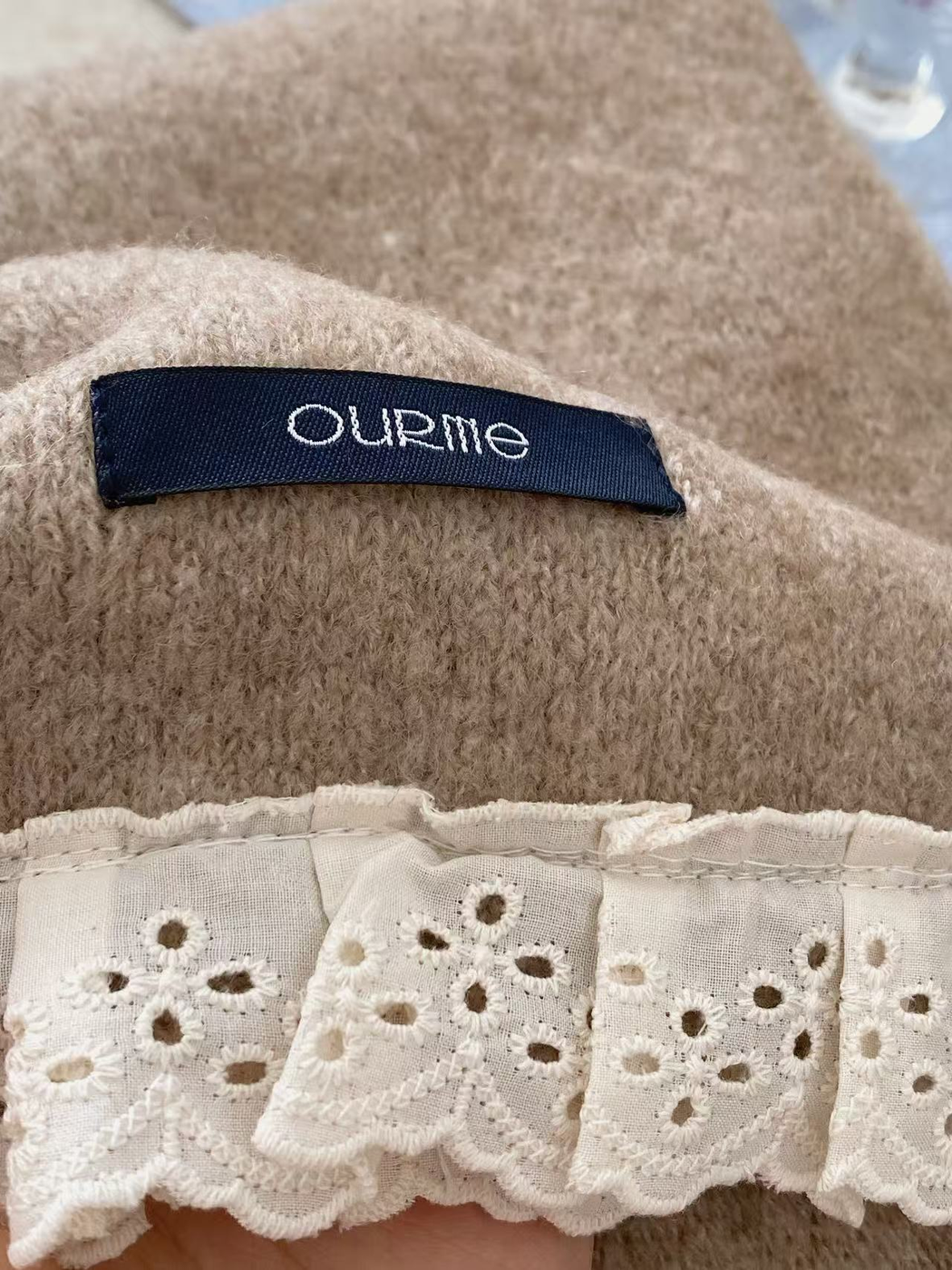 Close-up of brushed scarf texture, brand label and floral eyelet lace trim