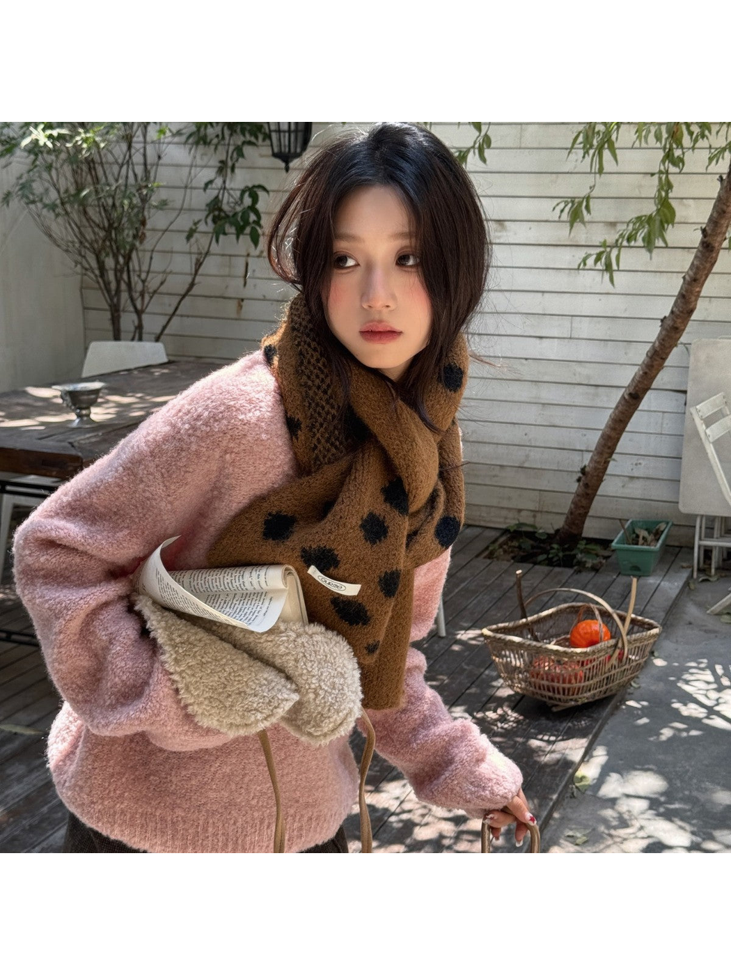 Camel Black irregular polka dot scarf worn with a pink sweater outdoors