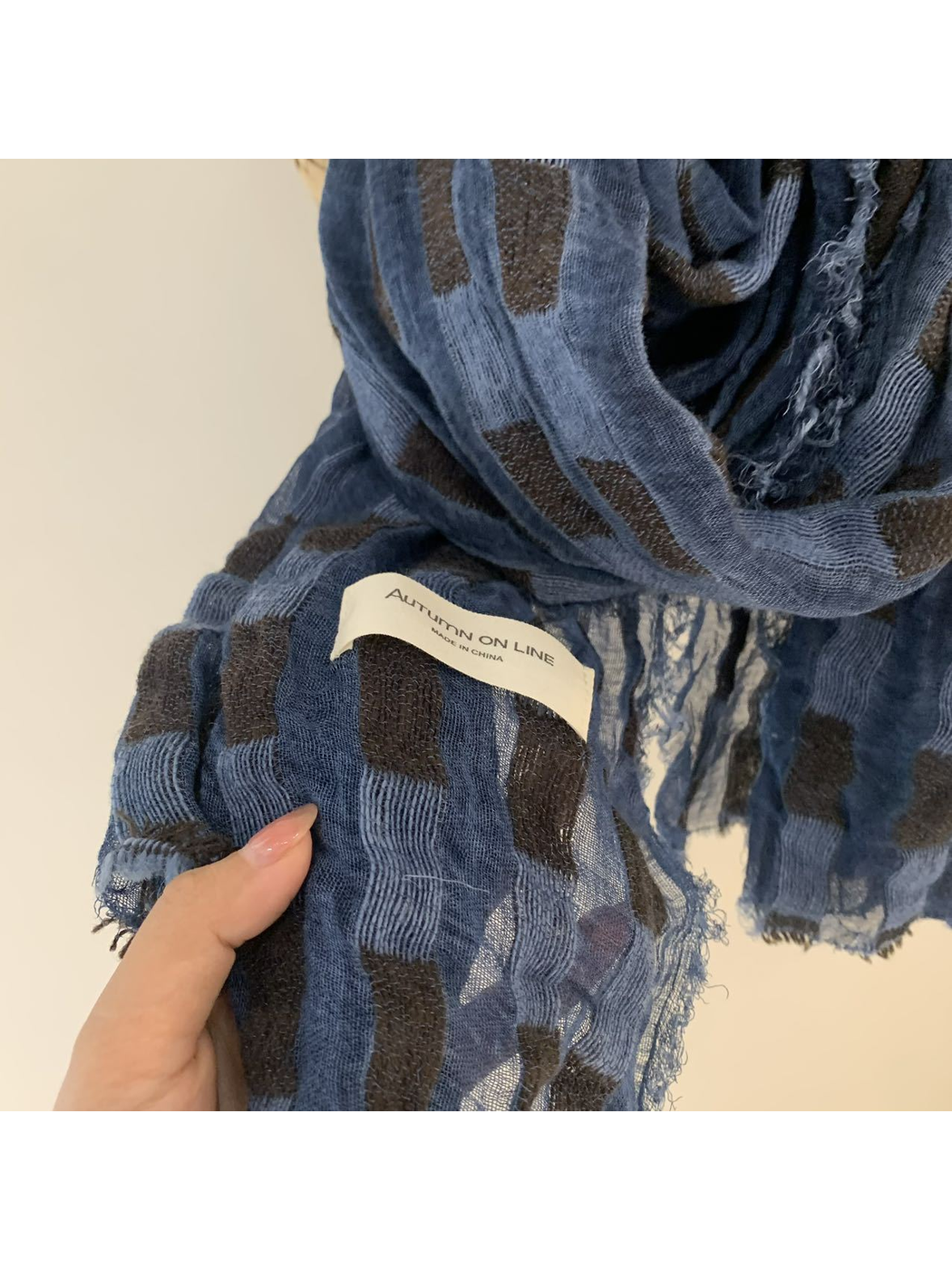 Close-up of the blue scarf's semi-sheer weave, block pattern and frayed edge