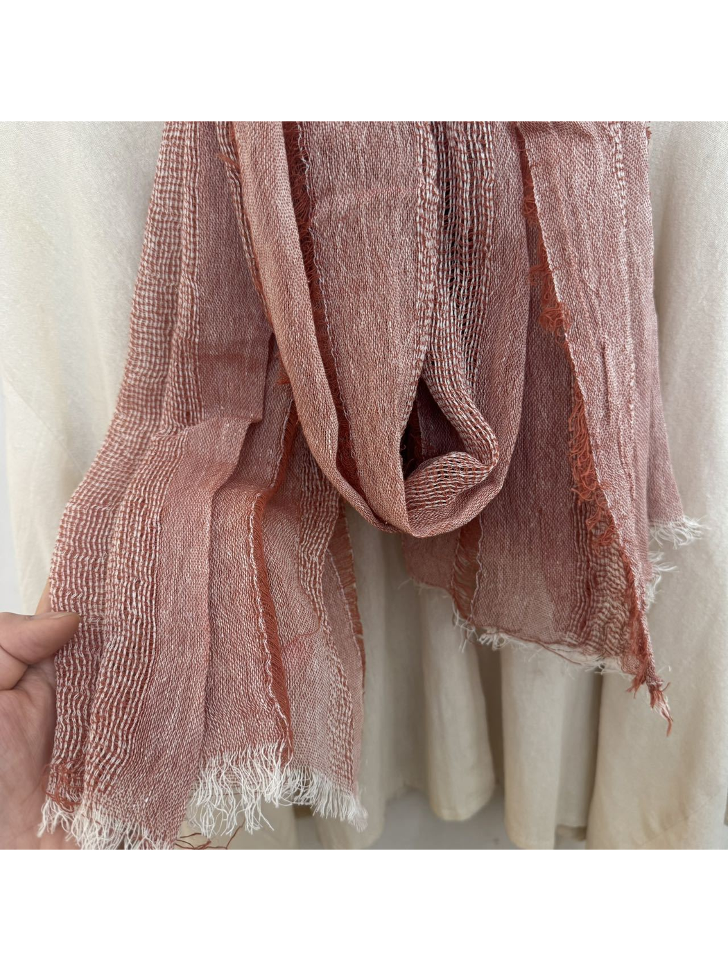 Close-up of pink scarf with alternating open-weave bands, crinkled texture and fringed edge