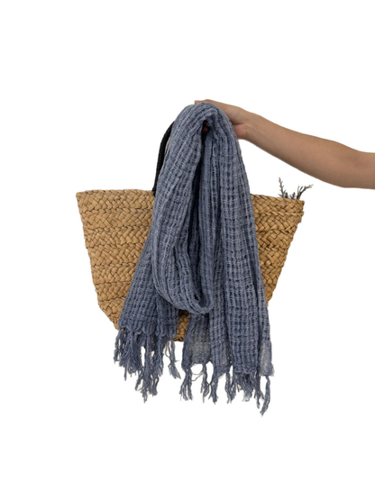 Openwork scarf with fringed ends draped over a woven tote