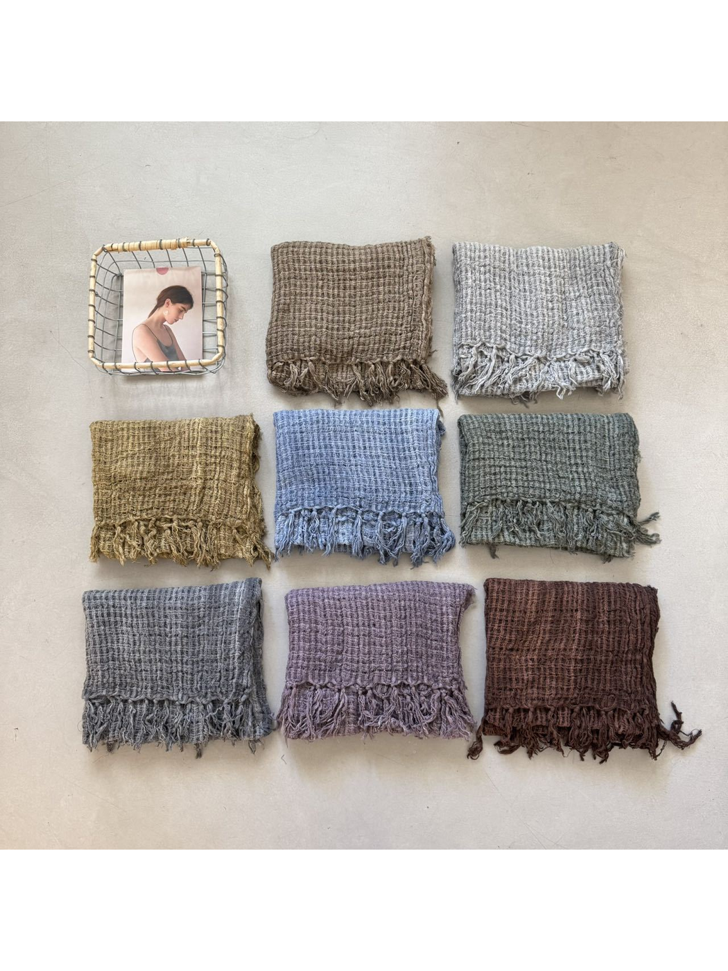 Eight color variations of the openwork fringed scarf arranged in a flat lay