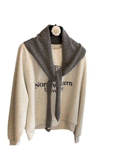 Dark gray triangle scarf tied over a cream sweatshirt on a white background