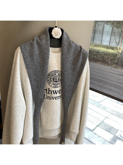 Dark gray triangle scarf draped open over a cream sweatshirt