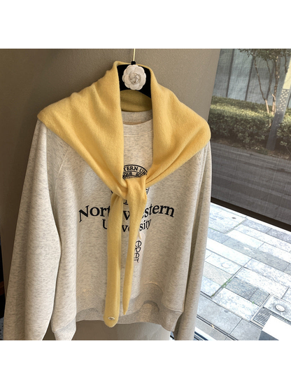 Yellow triangle scarf tied over a cream sweatshirt