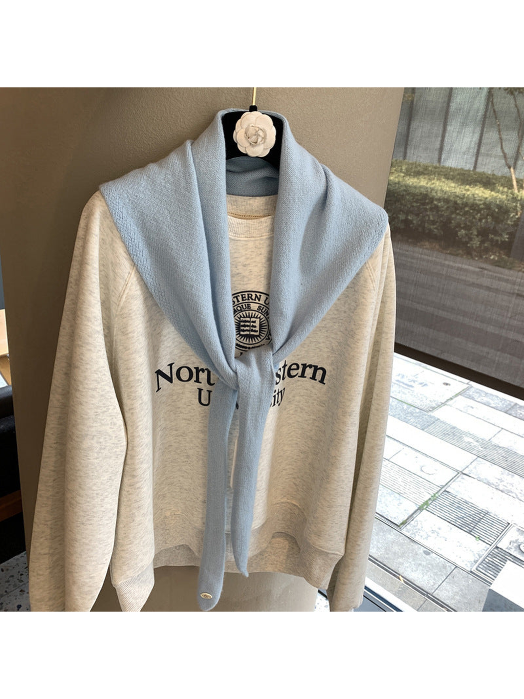 Light Blue triangle scarf tied over a cream sweatshirt