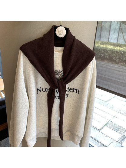 Burgundy triangle scarf tied over a cream sweatshirt