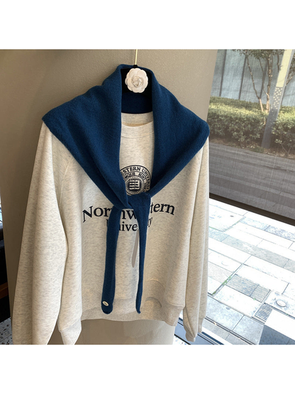 Navy triangle scarf tied over a cream sweatshirt