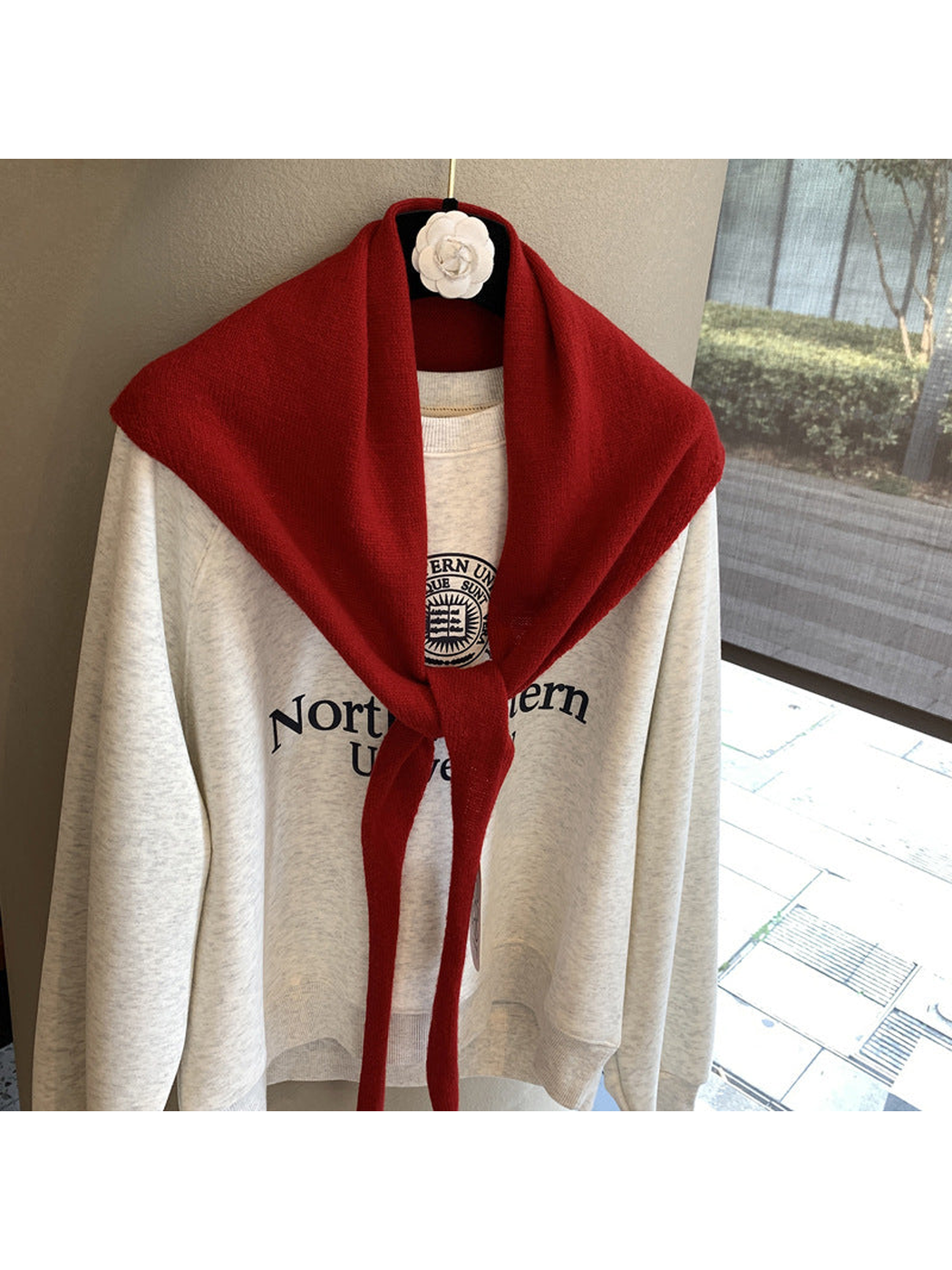 Red triangle scarf tied over a cream sweatshirt