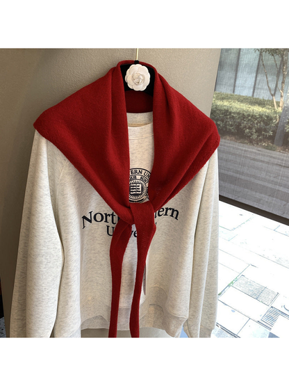 Red triangle scarf tied over a cream sweatshirt