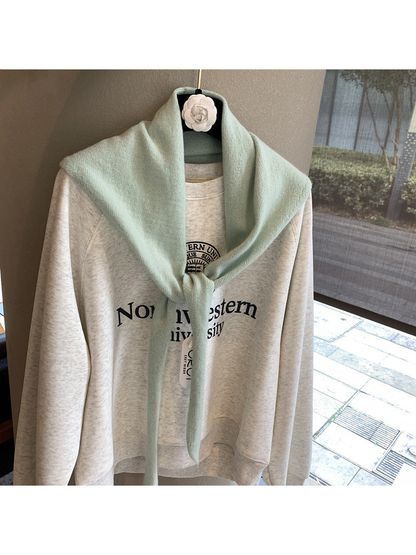 Mint triangle scarf tied over a cream sweatshirt