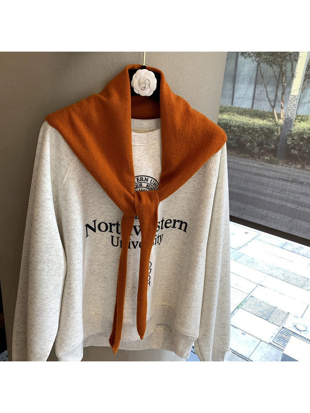 Orange triangle scarf tied over a cream sweatshirt