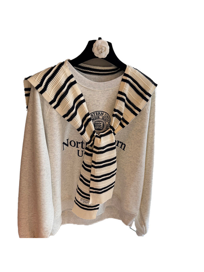 Ivory and black striped knit scarf tied over a sweatshirt on a white background