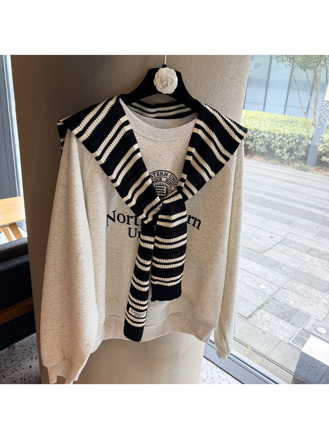 Black and ivory striped knit scarf tied over a sweatshirt
