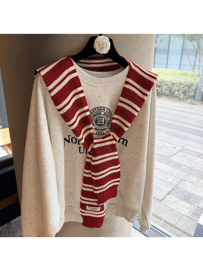 Red and ivory striped knit scarf tied over a sweatshirt