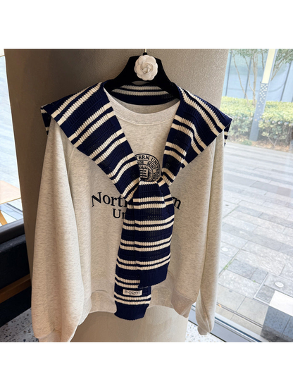 Navy and ivory striped knit scarf tied over a sweatshirt
