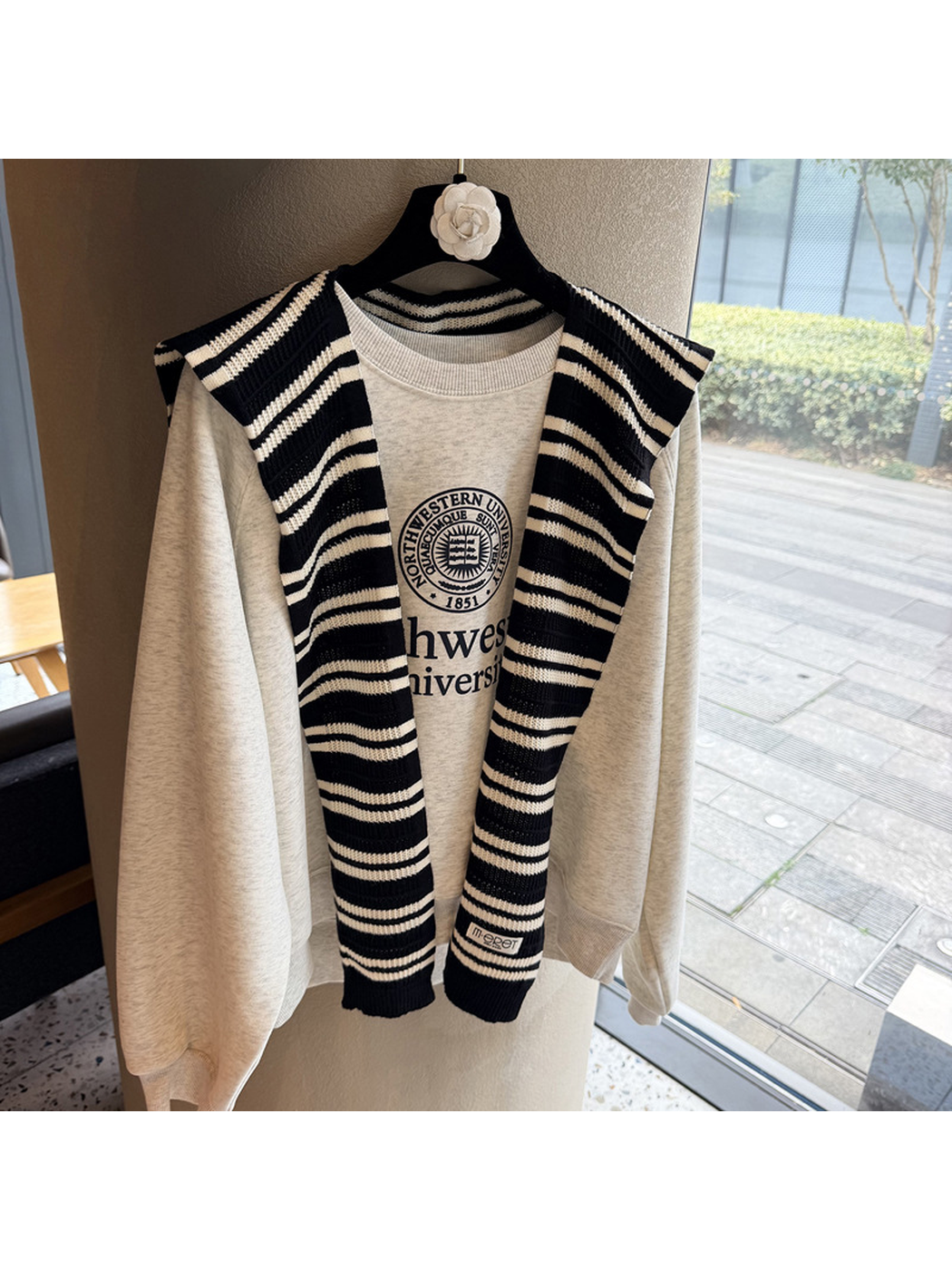 Black and ivory striped knit scarf hanging untied over a sweatshirt
