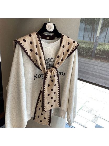 Beige polka-dot scarf with dark contrast border in a tied front drape