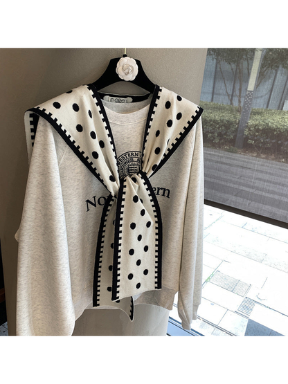Ivory polka-dot scarf with black contrast border in a tied front drape