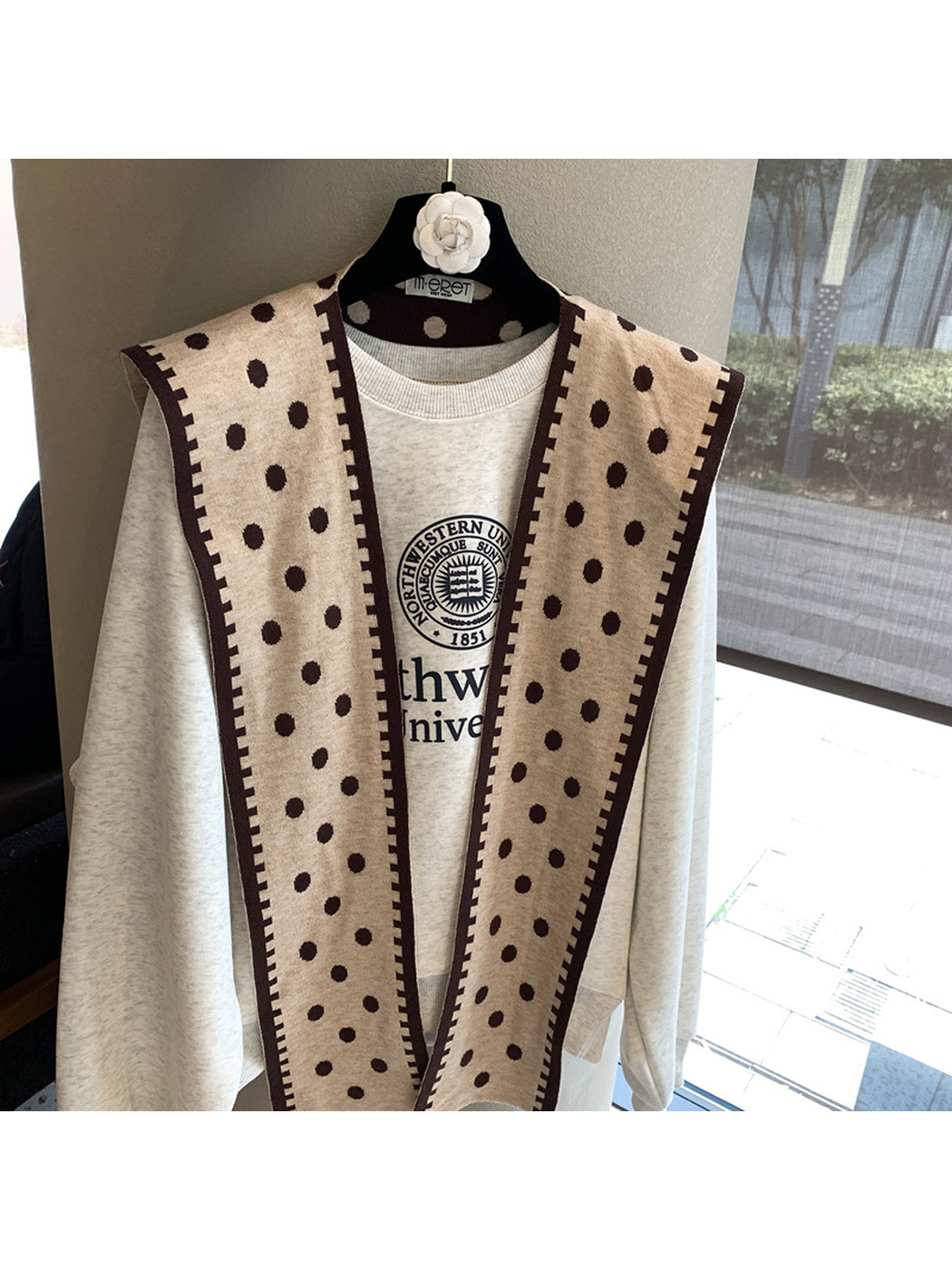 Beige polka-dot scarf hanging open to show the contrasting geometric border