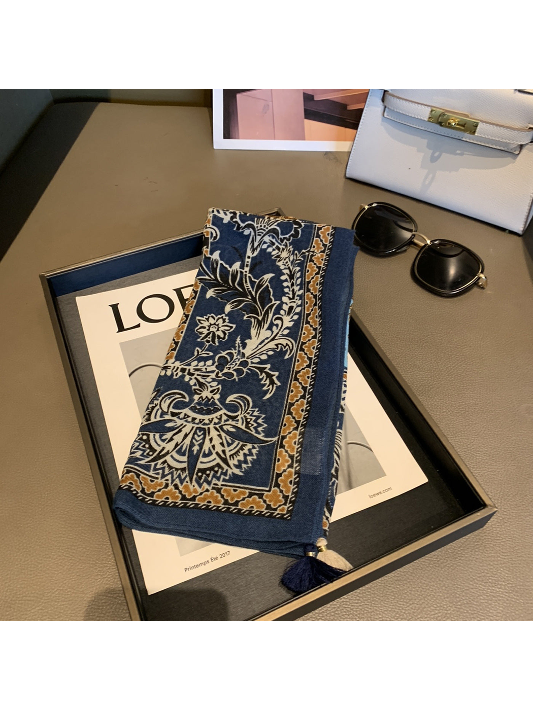 Folded navy scarf showing an ornamental floral border and corner tassels