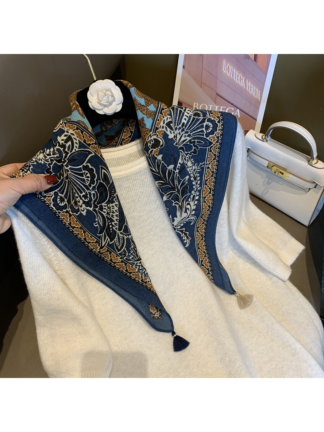 Navy patterned scarf draped over a white sweater on a hanger