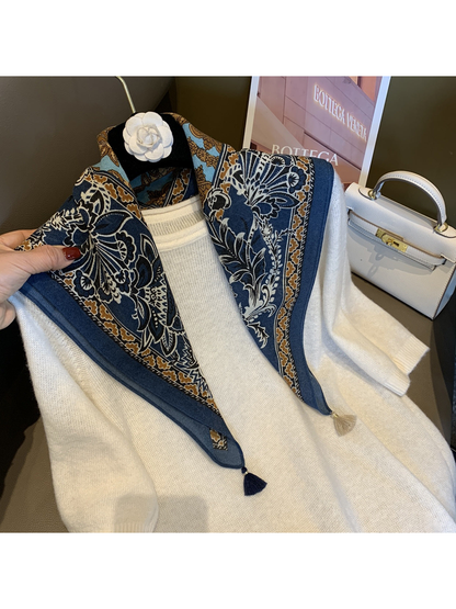 Navy patterned scarf draped over a white sweater on a hanger