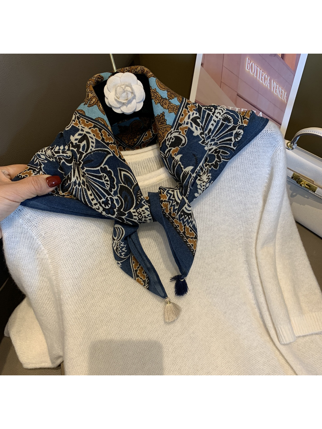 Navy patterned scarf tied at the neckline of a white sweater