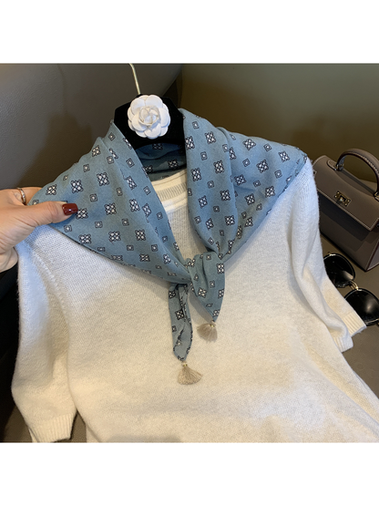Blue patterned scarf tied at the neck over a white sweater