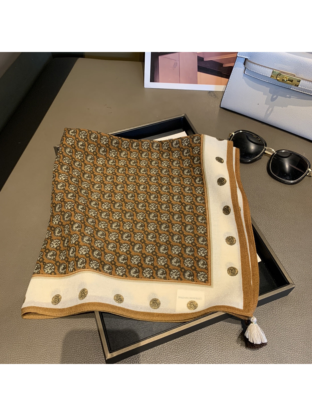 Camel-brown patterned square scarf folded to show the cream medallion border and corner tassels