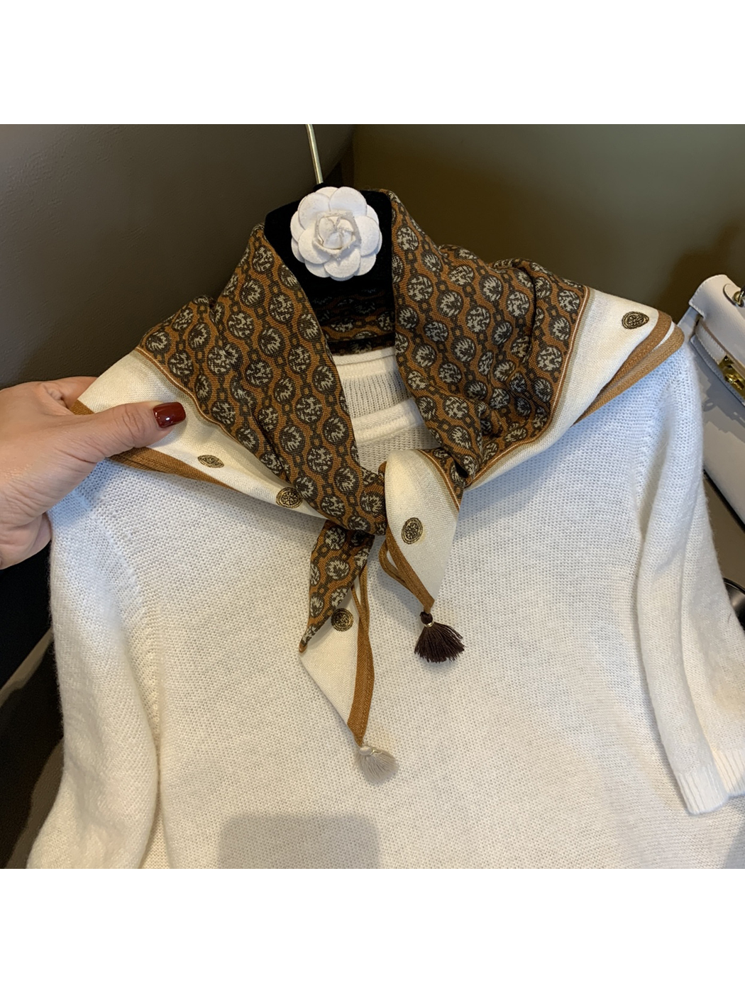 Camel-brown patterned square scarf tied over a white top with contrasting corner tassels