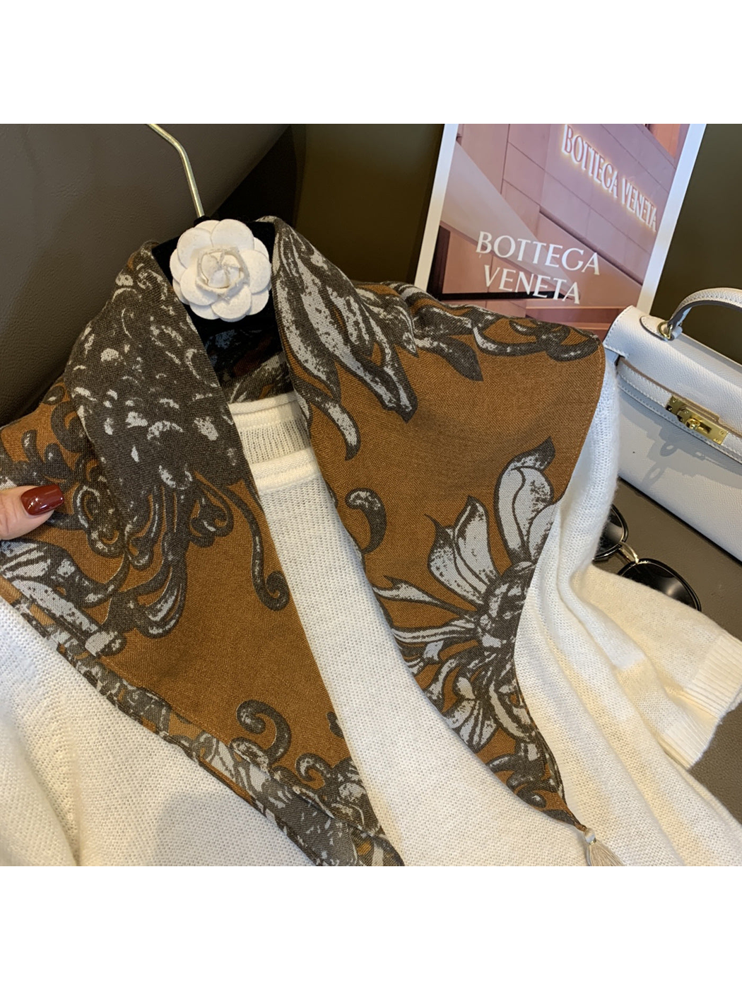 Warm brown floral scarf draped around the neckline of a white sweater