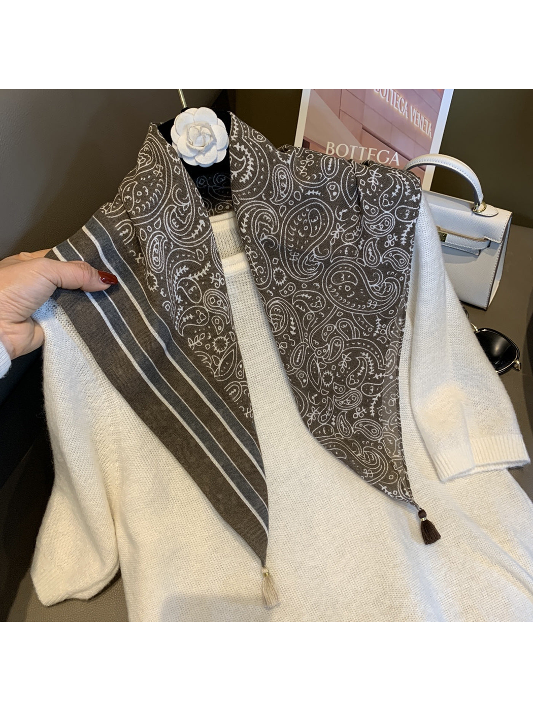 Army Green paisley scarf draped over a white sweater to show the striped border and tassels