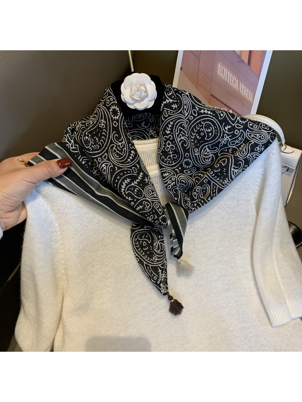 Black paisley scarf tied at the neckline over a white sweater