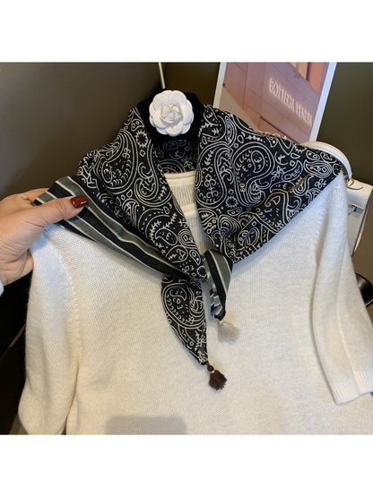 Black paisley scarf tied at the neckline over a white sweater