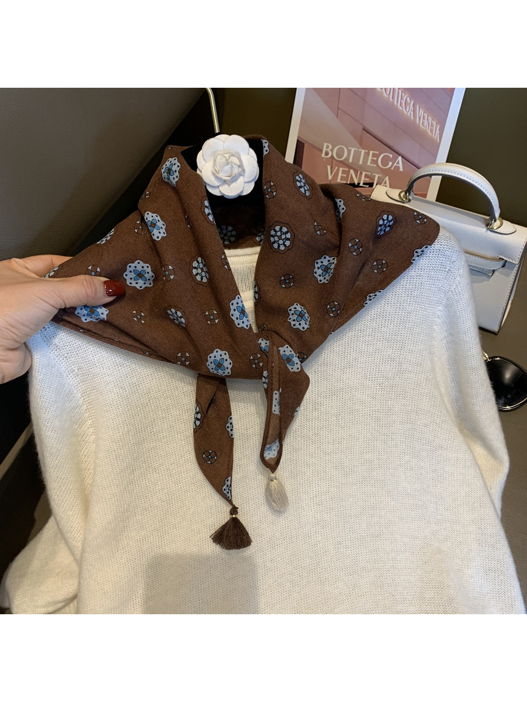 Brown floral medallion scarf tied at the neck over a white sweater