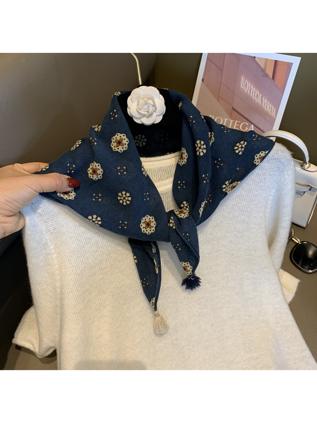 Navy floral medallion scarf looped and tied at the neck over a white sweater