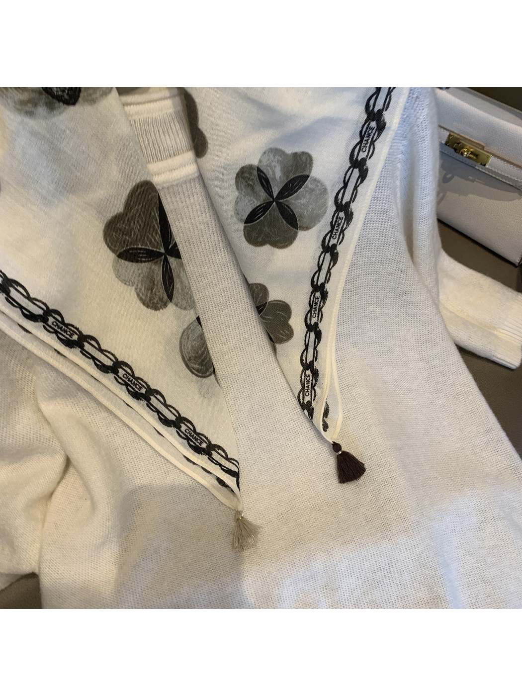 Close-up of the Ivory scarf's floral print, chain-style border, stitched edge and tassels