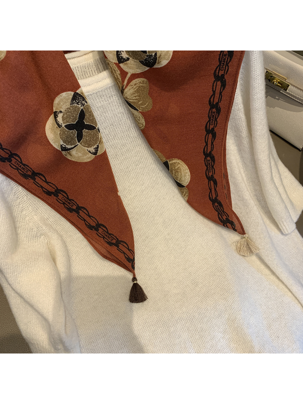 Close-up of the Orange Red scarf's floral print, chain-style border and contrasting tassels