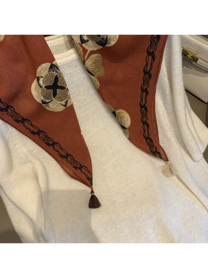 Close-up of the Orange Red scarf's floral print, chain-style border and contrasting tassels