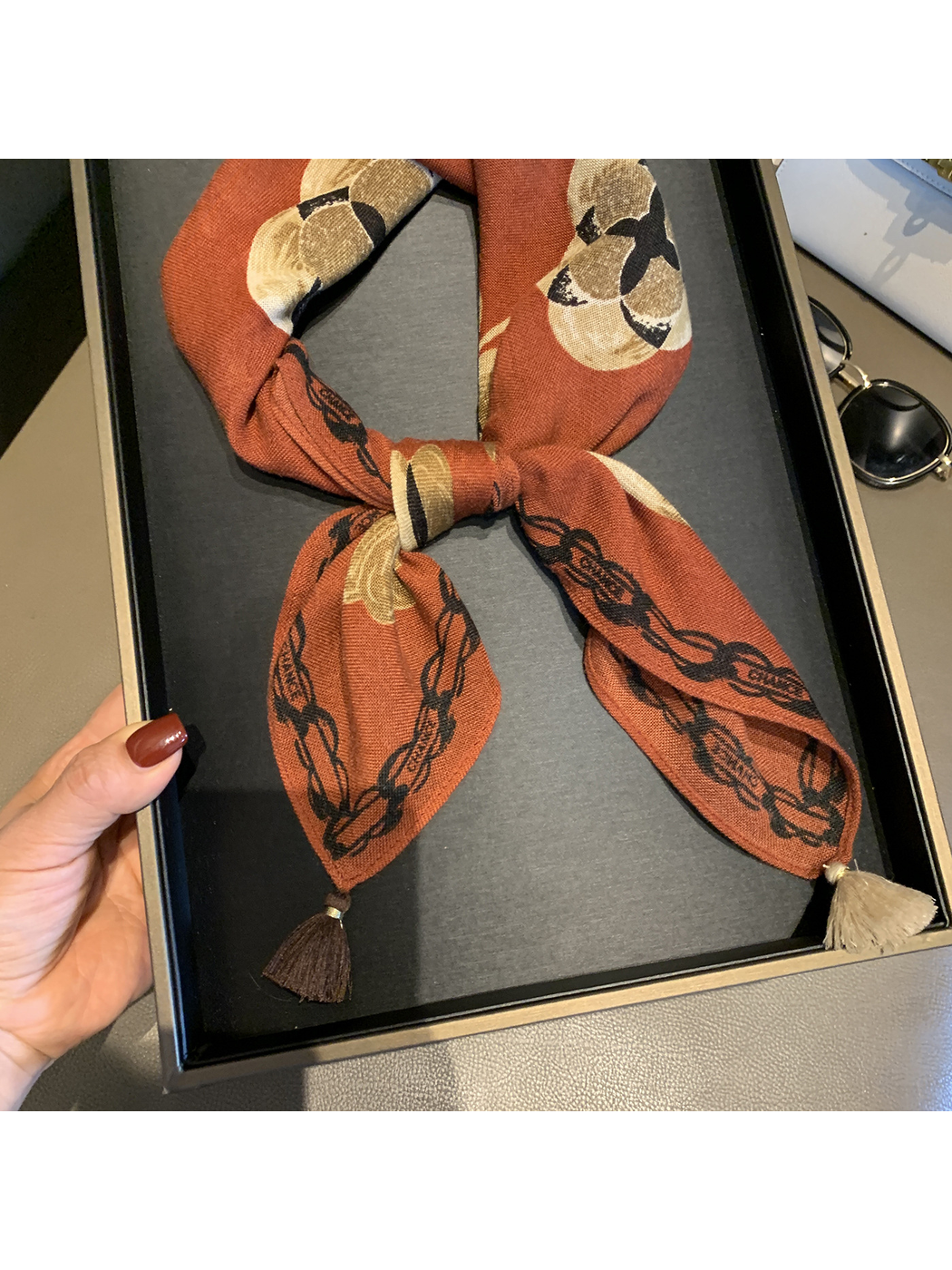 Close-up of the Orange Red floral scarf's bow knot, chain-style border and tassel ends