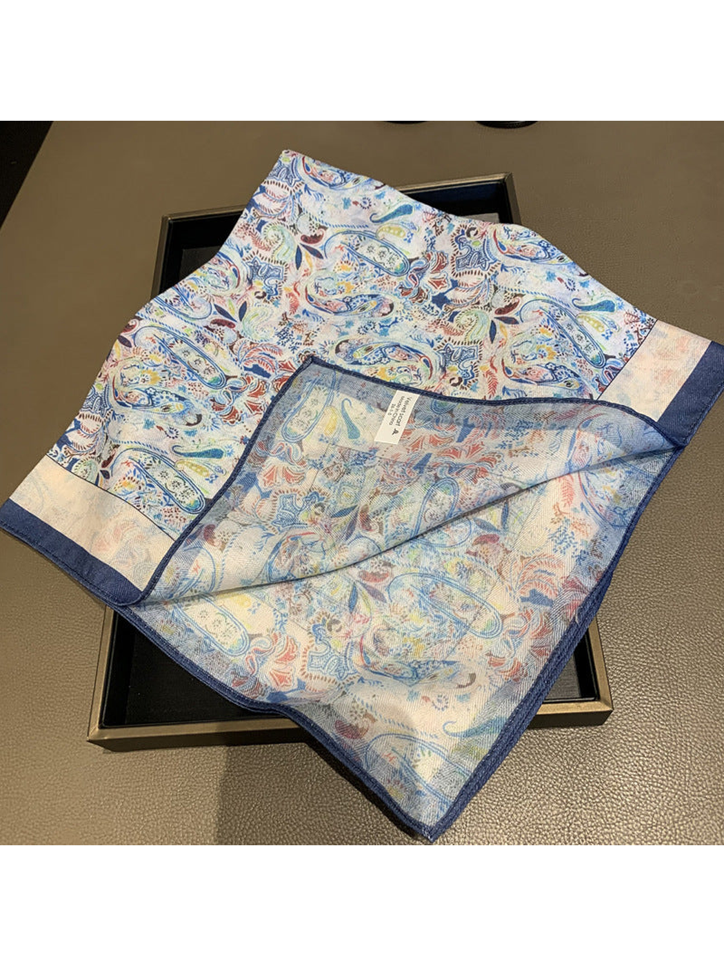 Close view of the multicolor paisley scarf and navy stitched border