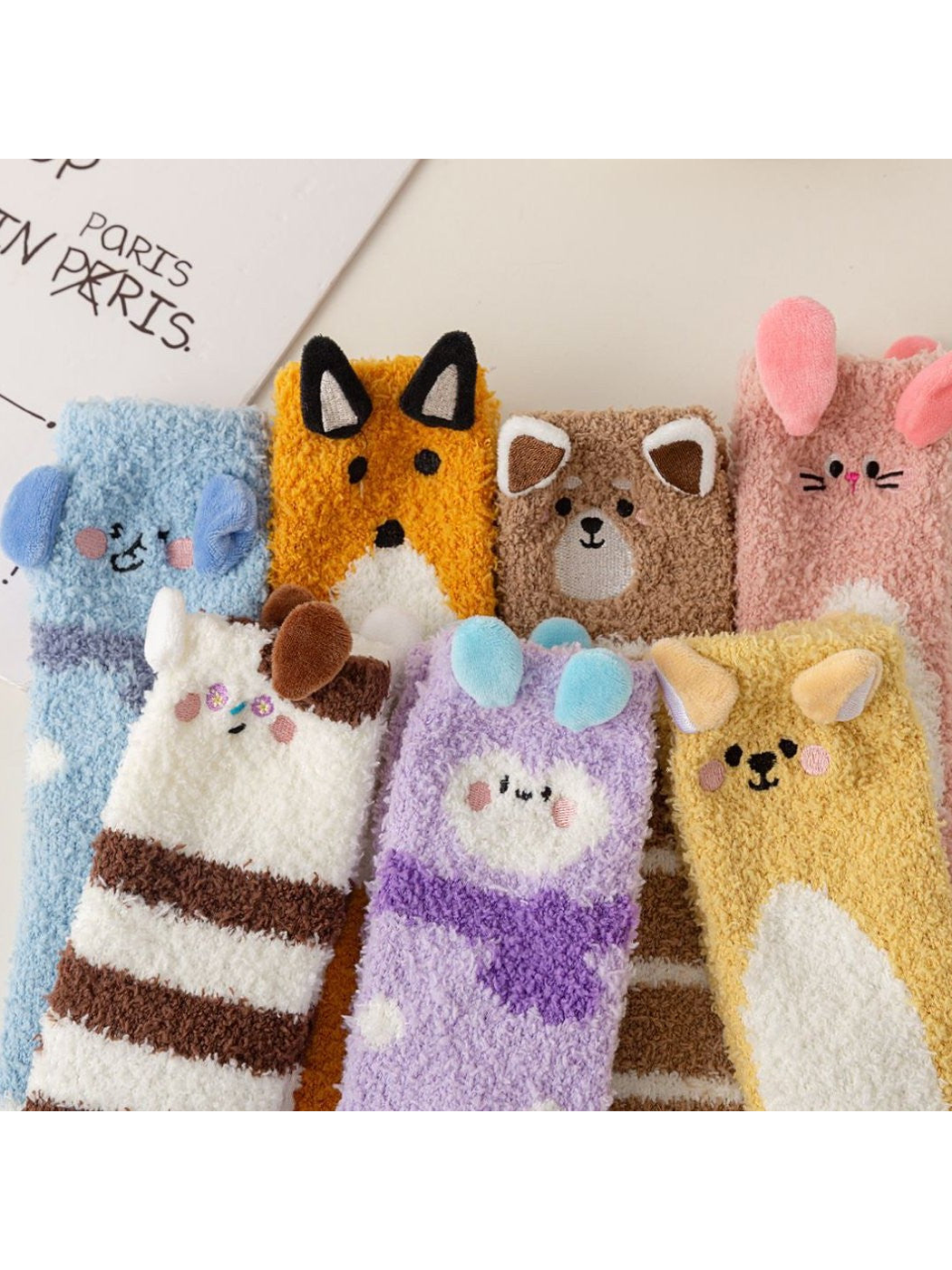 Close group view of colorful fuzzy socks with animal faces and raised ear accents