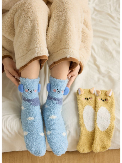 Light Blue animal character socks worn beside a Yellow pair on a bed