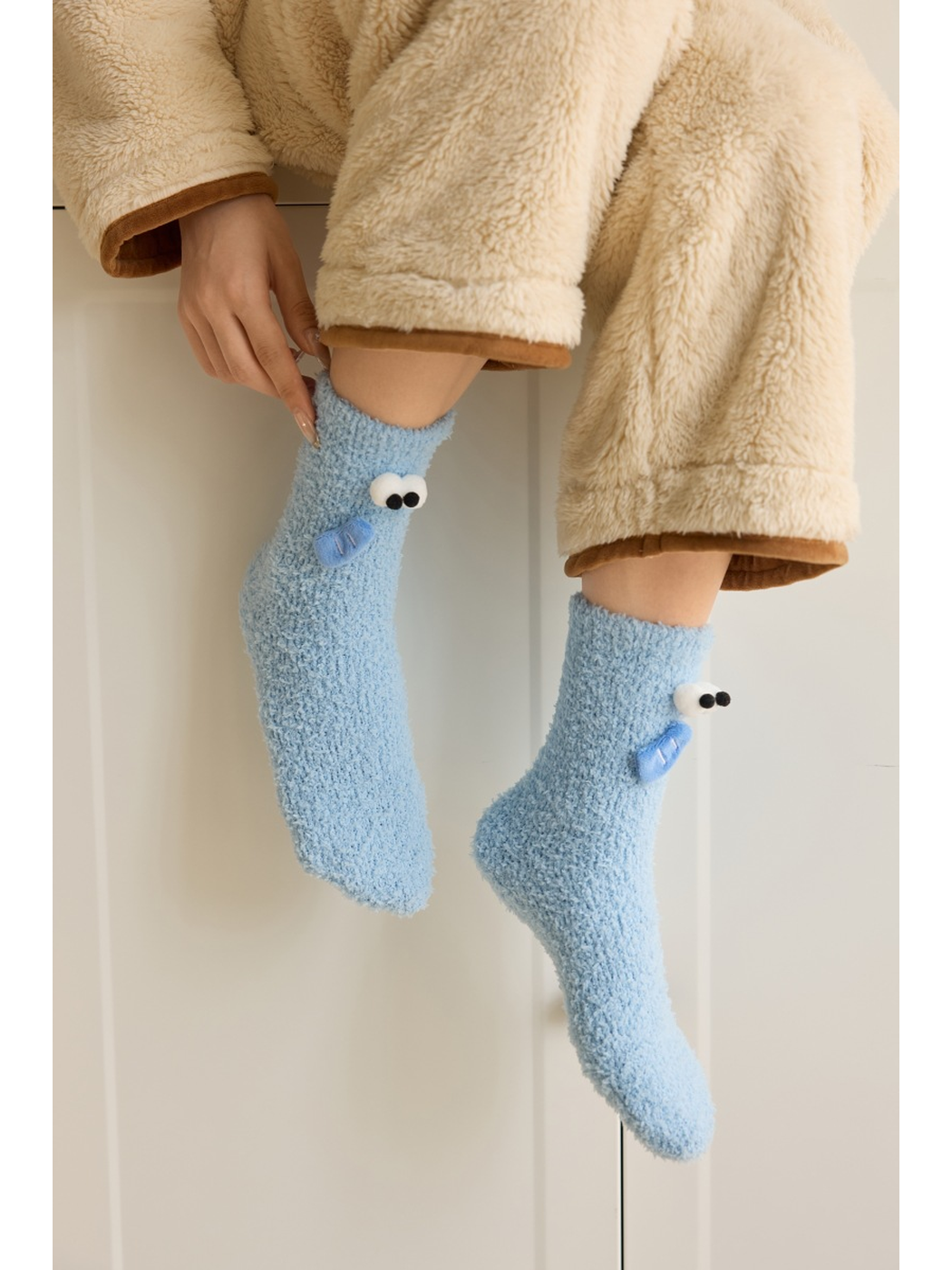 Light Blue fuzzy cartoon face socks worn while seated