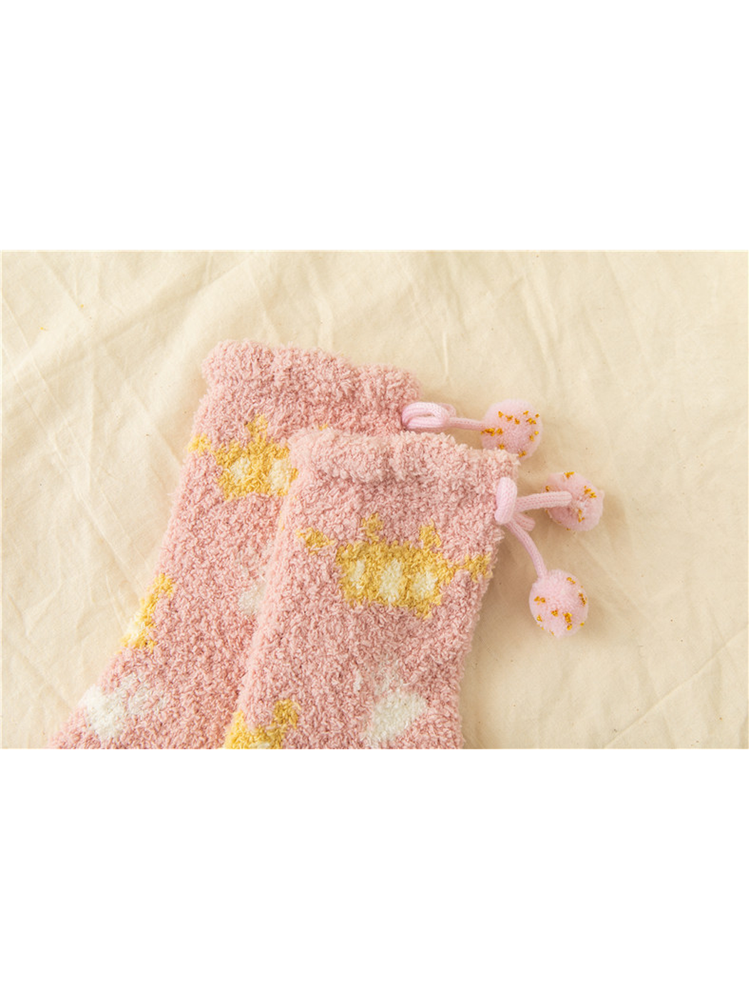 Close-up of Light Pink fuzzy socks with fold-over cuffs and pom-pom ties